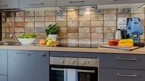 Een moderne keuken met grijze kastjes, een roestvrijstalen oven en een betegelde achterwand met tekst.