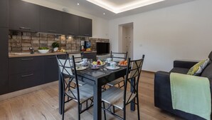 Een moderne keuken met donkere kastjes, een betegelde achterwand en een eethoek met een tafel voor vier personen.