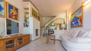 Een woonkamer met een witte bank, een houten kast en kunstwerken aan de muur.