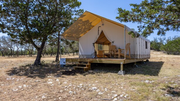 A single-story, A-frame-style tent with a wooden deck and seating area.