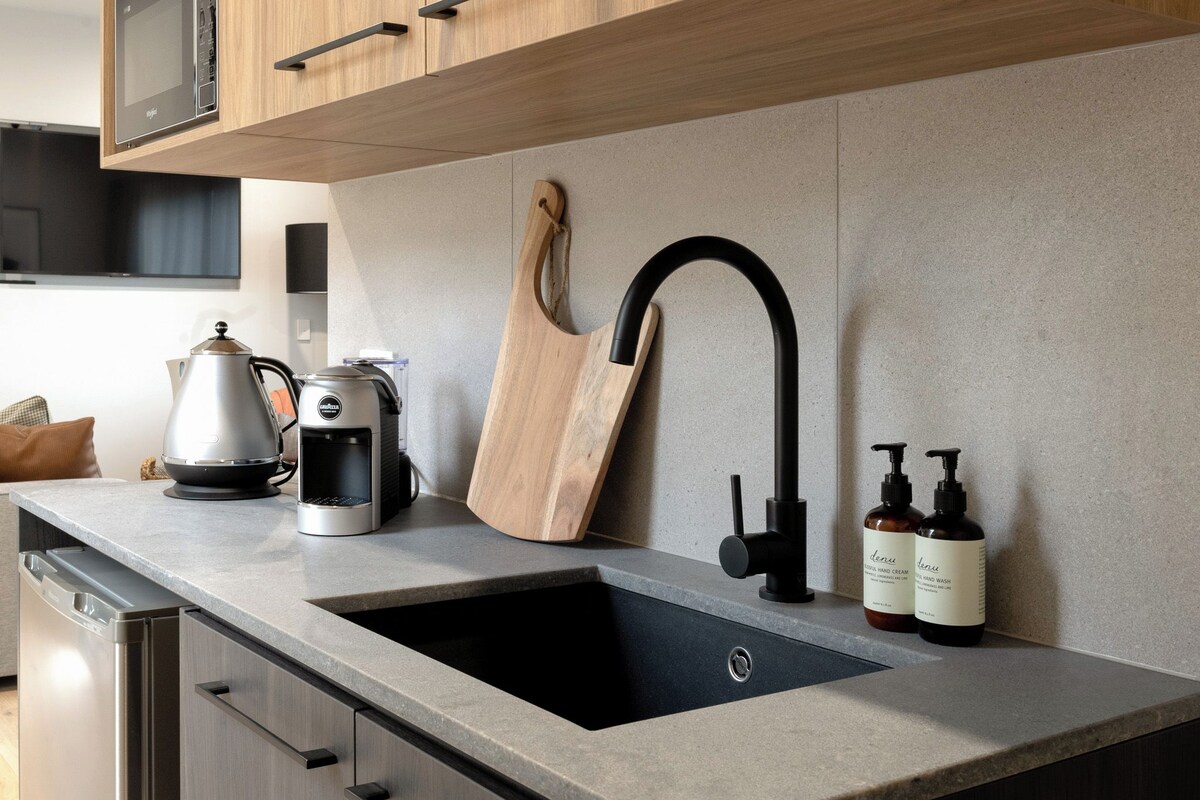 A modern kitchen with a built-in sink, wooden cabinets, a stainless steel coffee maker, and a knife block.
