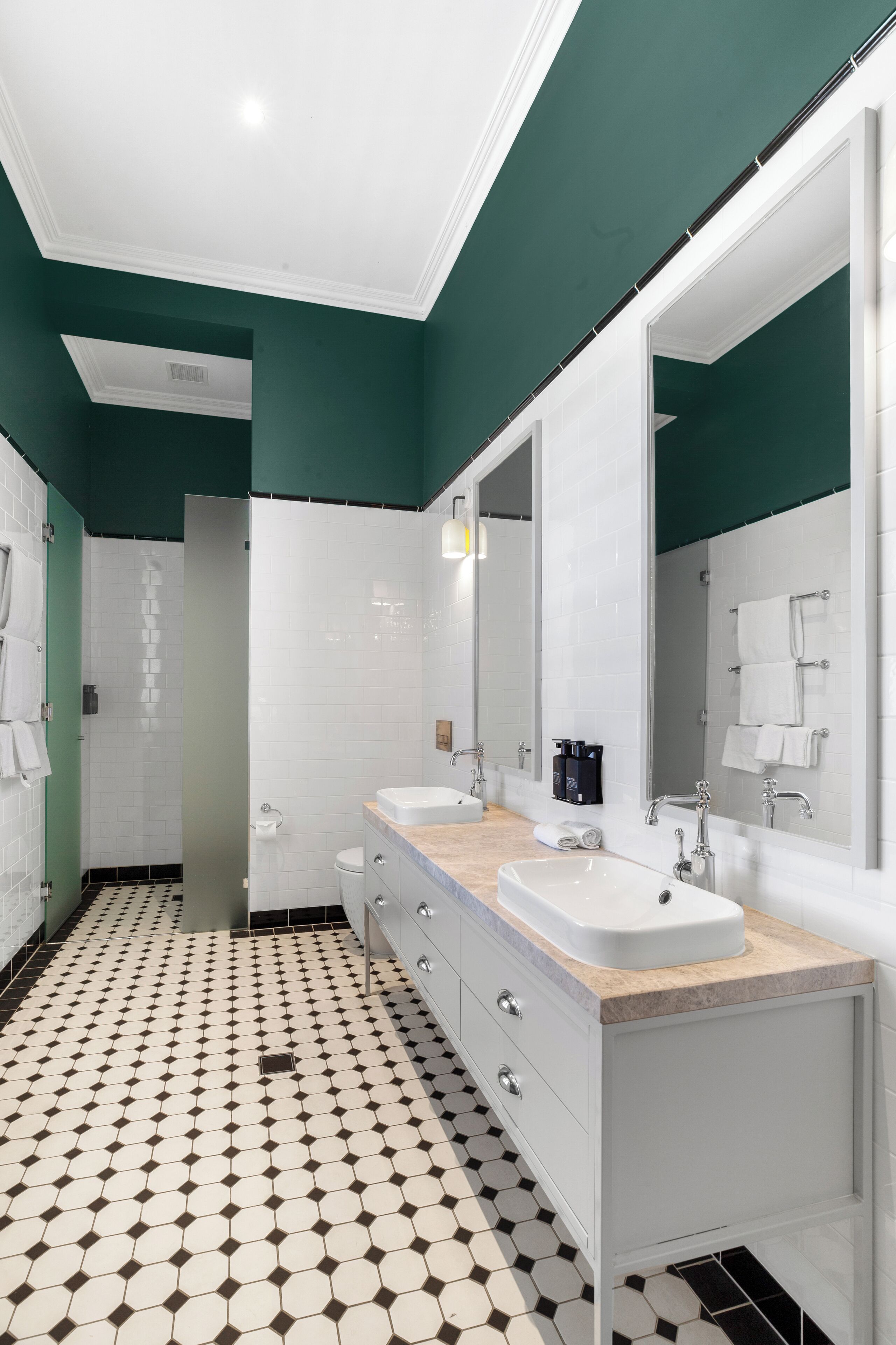 A modern bathroom with two sinks, a large mirror, and a patterned floor.