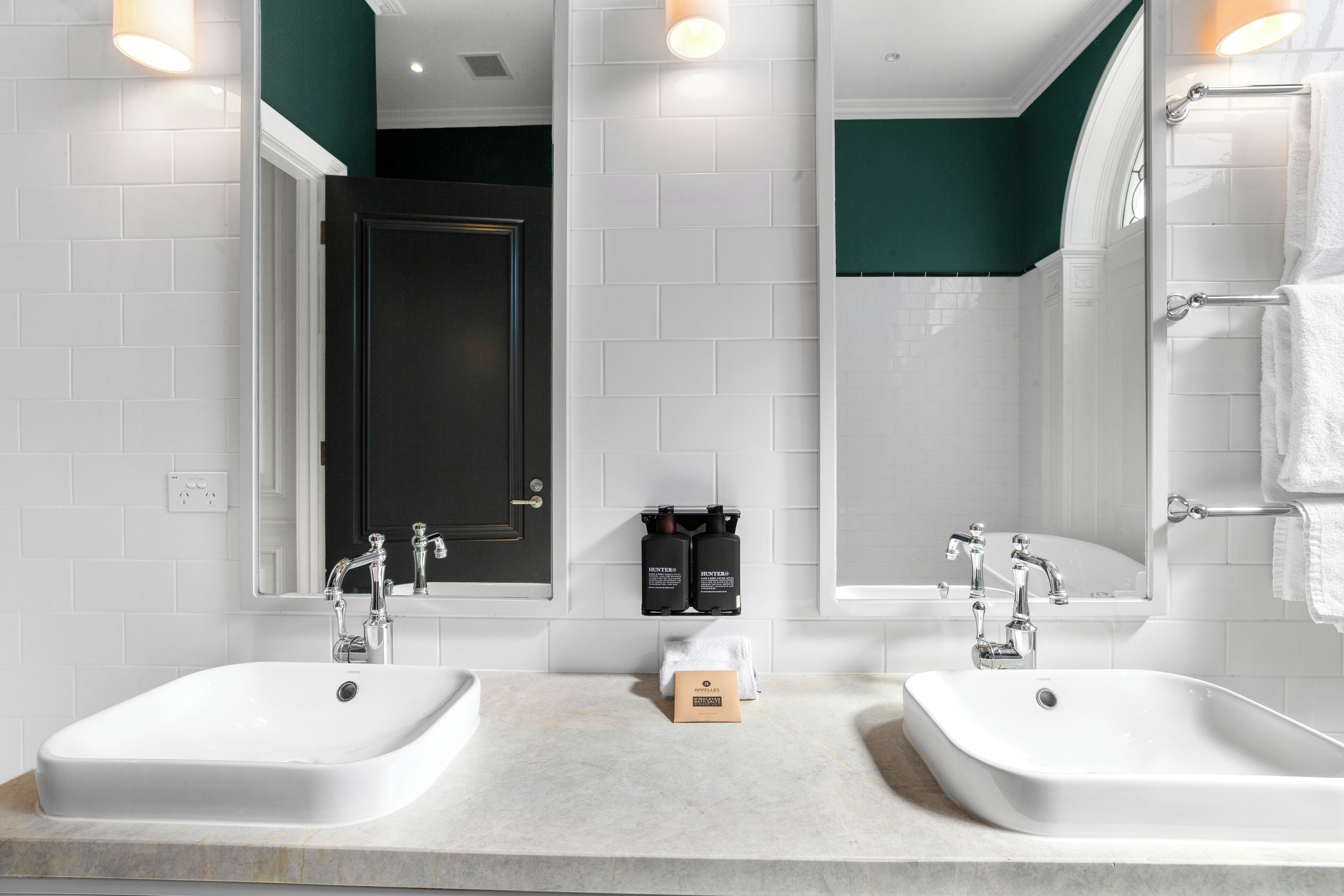 A modern bathroom with two sinks, a mirror, and a shower.