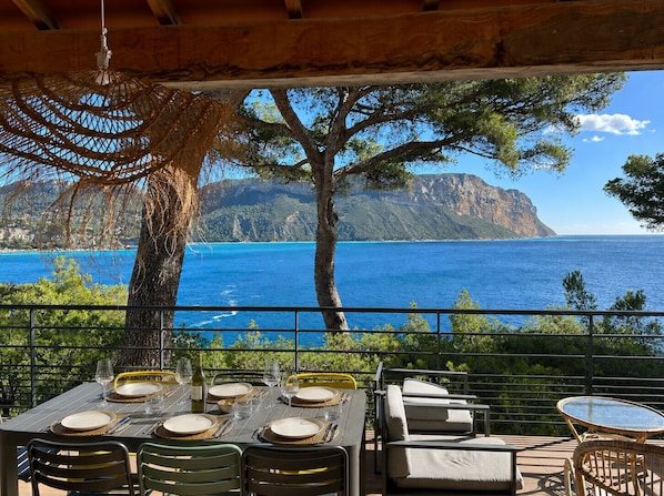 An outdoor dining area with a view of the sea and a mountain.