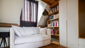 Un canapé blanc avec des coussins, une bibliothèque en bois remplie de livres et un plancher en bois.