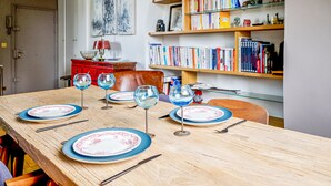 Une table à manger dressée avec des assiettes, des verres et des couverts, entourée d’étagères remplies de livres.