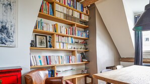 Un coin lecture confortable avec une bibliothèque en bois remplie de livres, un fauteuil en cuir et une petite table.