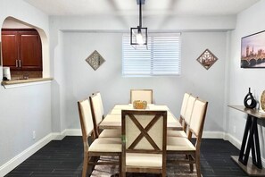 Una sala da pranzo con un tavolo rettangolare, sei sedie, un lampadario e decorazioni a parete.