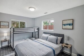 Una camera da letto con un letto a castello, un letto singolo, due comodini e una finestra.
