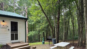 A cabin with a porch, a picnic table, and a trash can in a wooded area. - Trophy Buck sleeps 6, or rent all 4 for 20. Horseback riding across the Rd! (Laurelville)