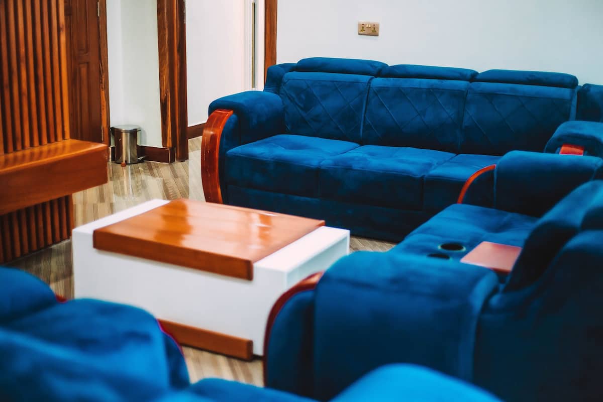 Una sala de estar con un sofá azul, una mesa de centro de madera y un cubo de basura pequeño.