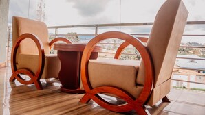 Een balkon met een houten tafel en twee stoelen met ronde houten poten.