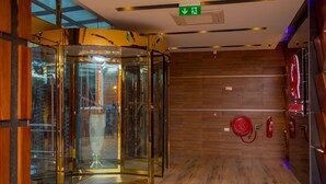 Een moderne lift met glazen deuren, houten vloeren en brandveiligheidsvoorzieningen.