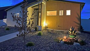 Una casa moderna con techo inclinado, puerta principal y un pequeño porche.