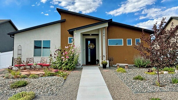 A modern house with a front porch, a small garden, and a clear sky. - Kokopelli House - Modern Fruita Retreat with Garage (Fruita)