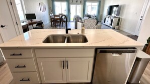 Una cocina con una isla grande, electrodomésticos de acero inoxidable y un comedor con mesa y sillas.