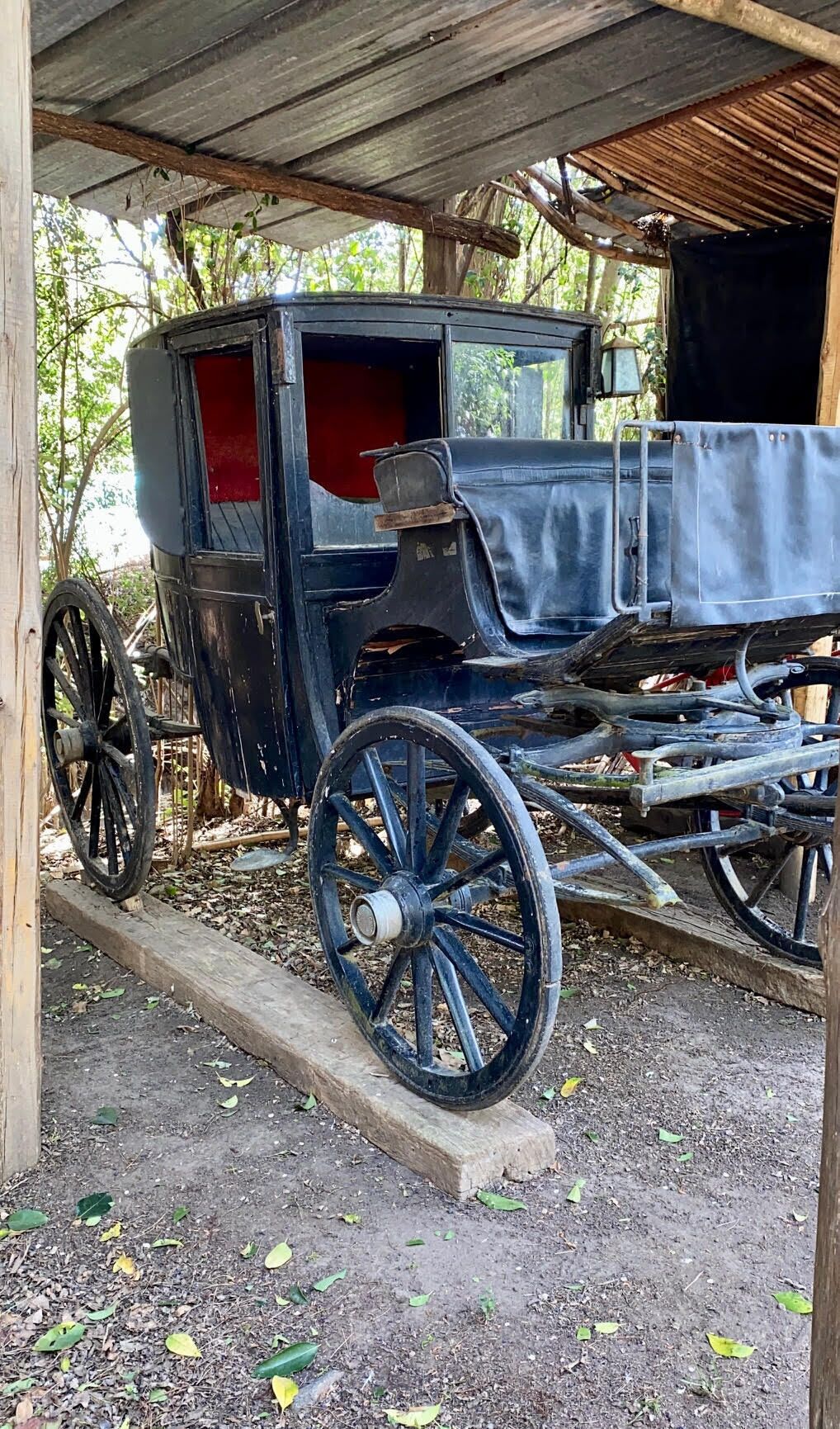 Un carruaje antiguo estacionado bajo un porche de madera.