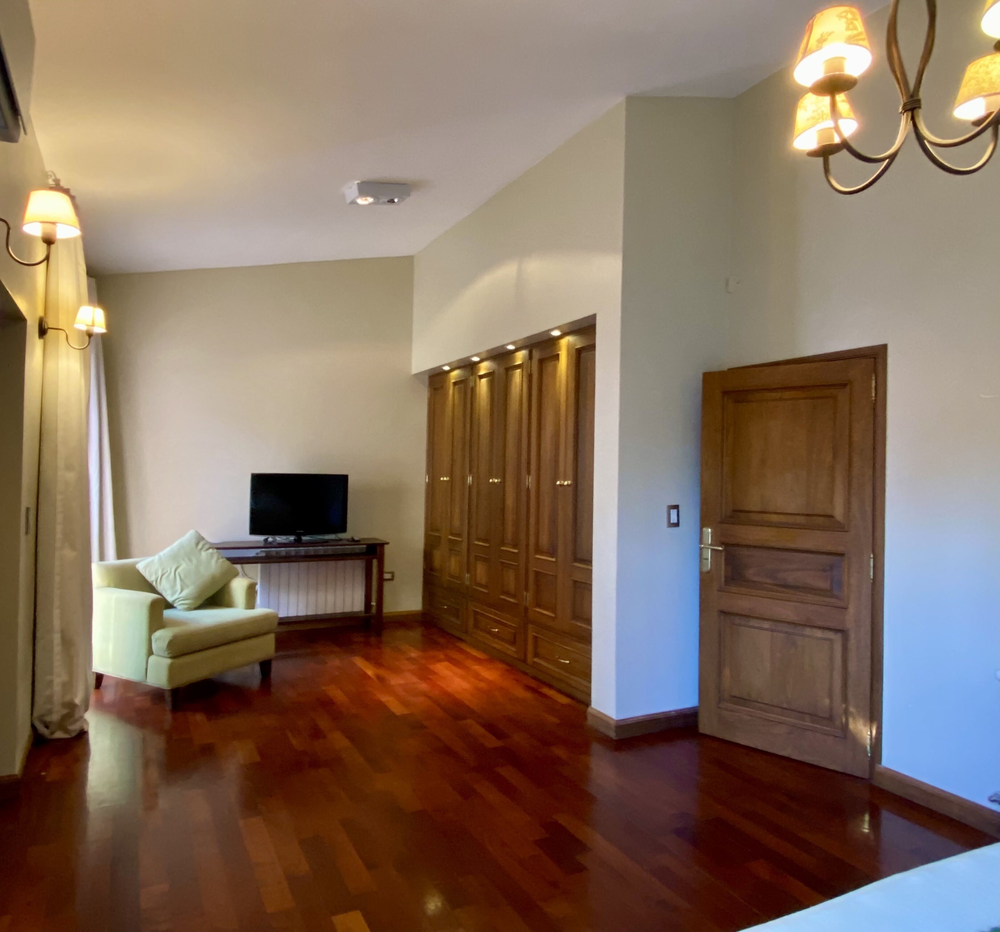 Un salon spacieux doté d’un plancher en bois, d’un téléviseur posé sur un meuble, d’un canapé et d’une armoire à plusieurs portes.