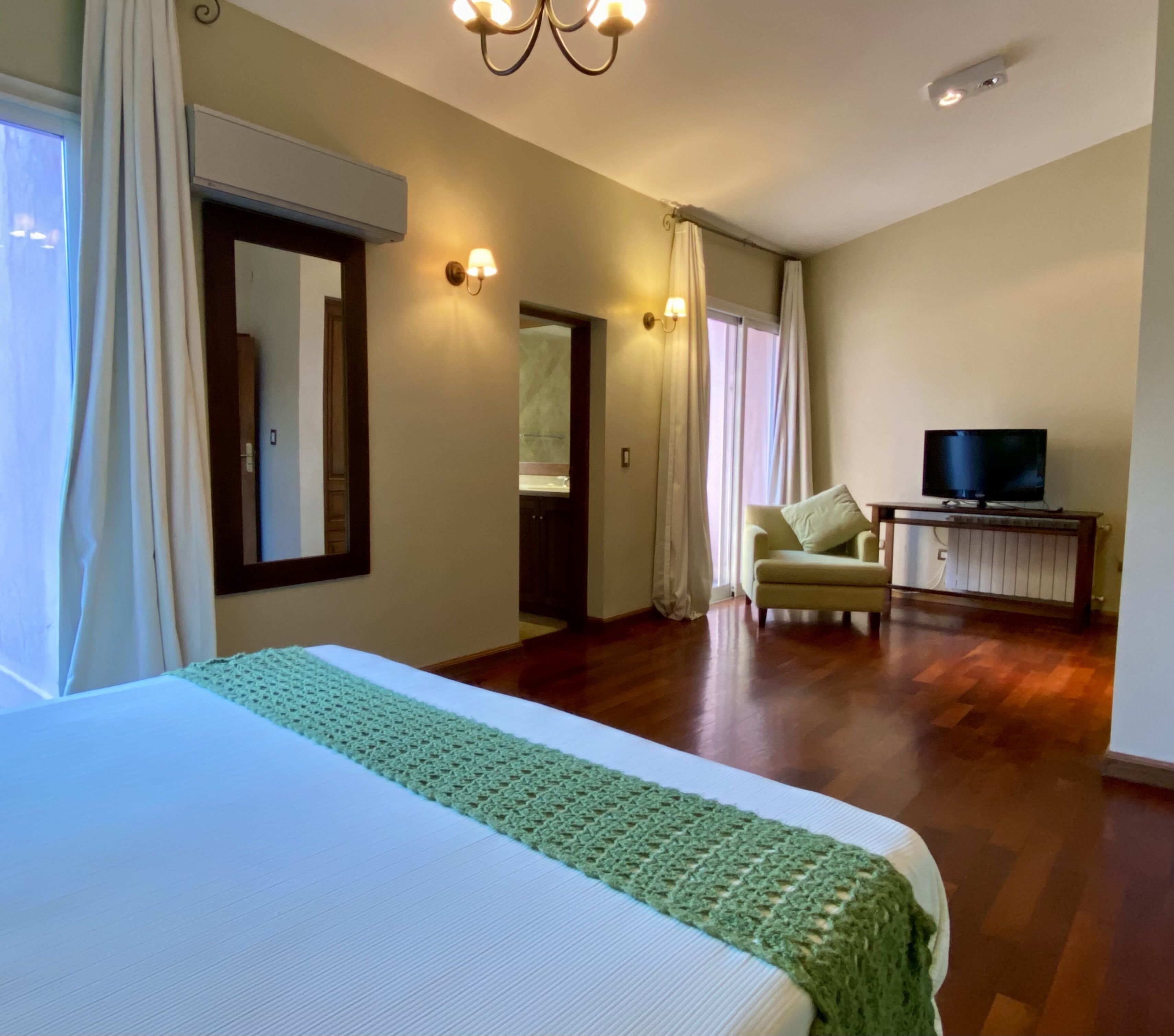 A hotel room with a large bed, a television, and a seating area with a chair and a small table.