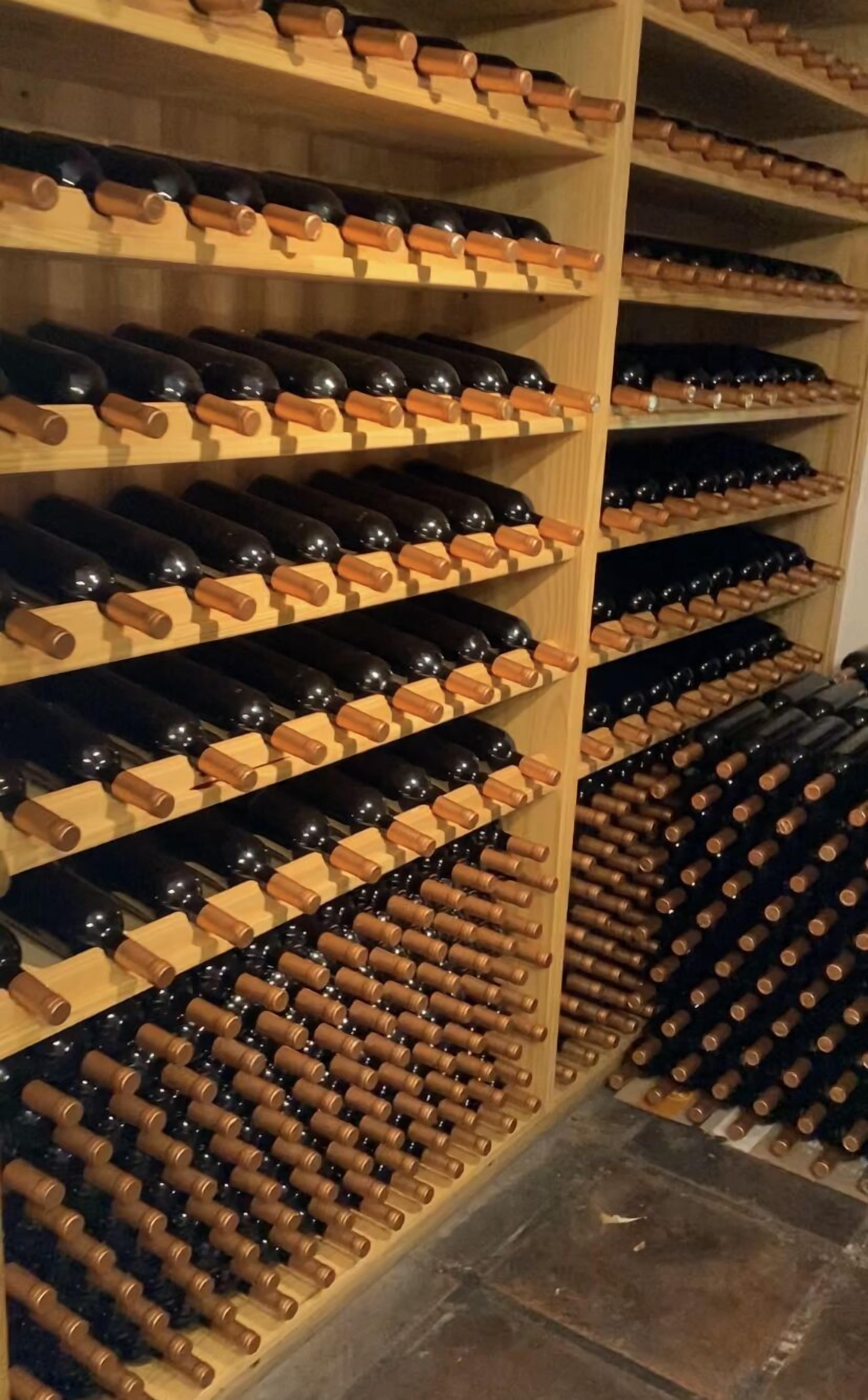 A wine cellar with wooden racks holding numerous wine bottles.