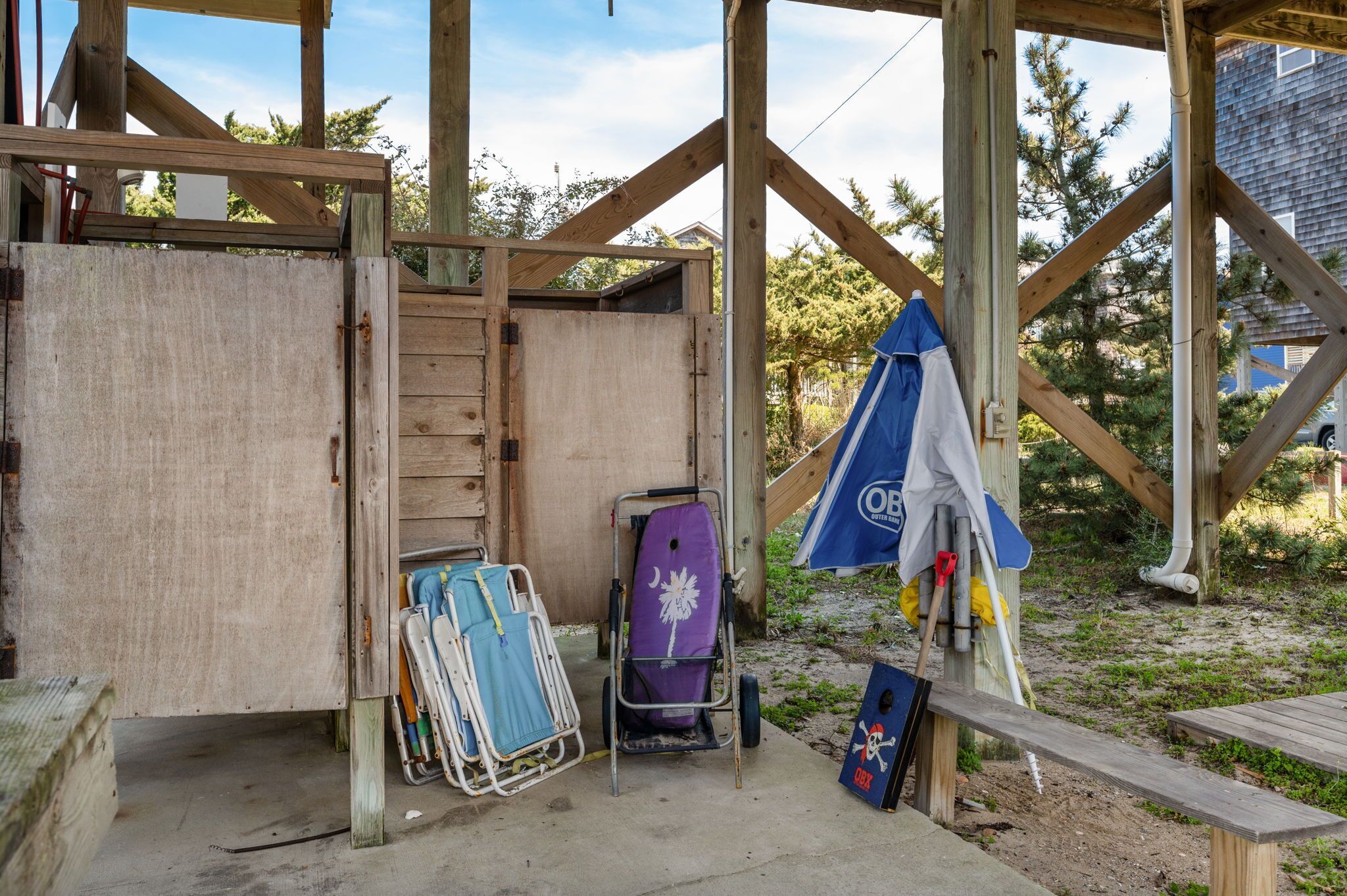 A wooden structure with a door, a bench, and a covered area with a blue umbrella.