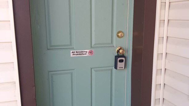 A green door with a number 2 sign, a 'No Smoking' sign, and a doorbell.