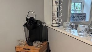 A kitchen counter with a coffee maker, a glass mug, and a plate.