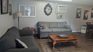 A living room with a grey sofa, a wooden coffee table, and a lamp.