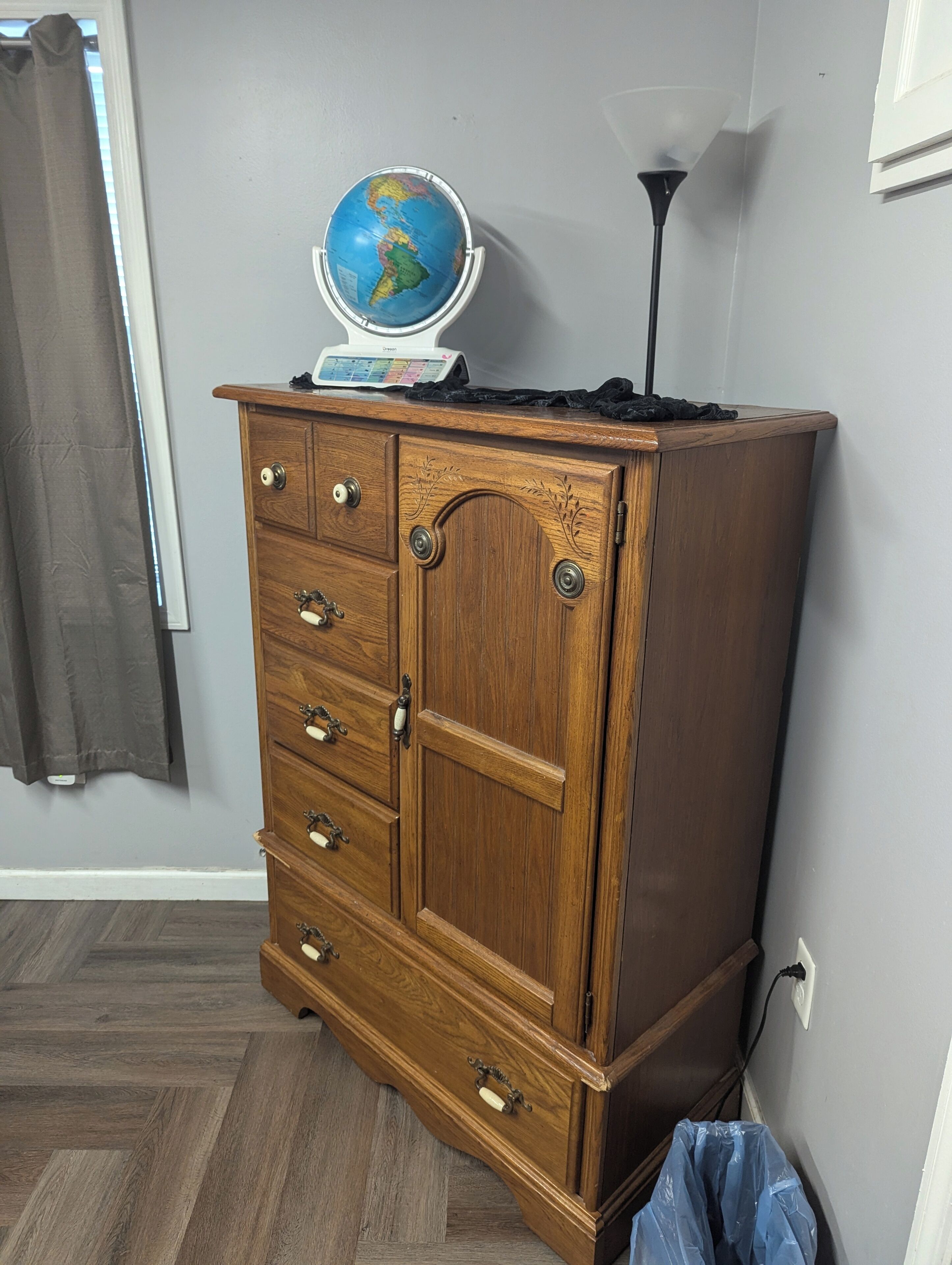 A wooden dresser with drawers and a globe on top.