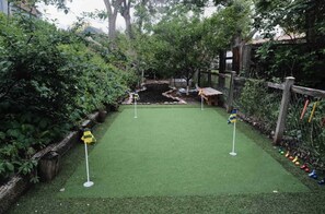Enjoy a round of golf in our backyard oasis, featuring a lush green course with holes and a setting.