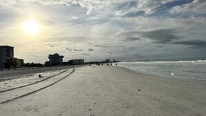 Ein Strand mit Fußspuren, Gebäuden und dem Meer.