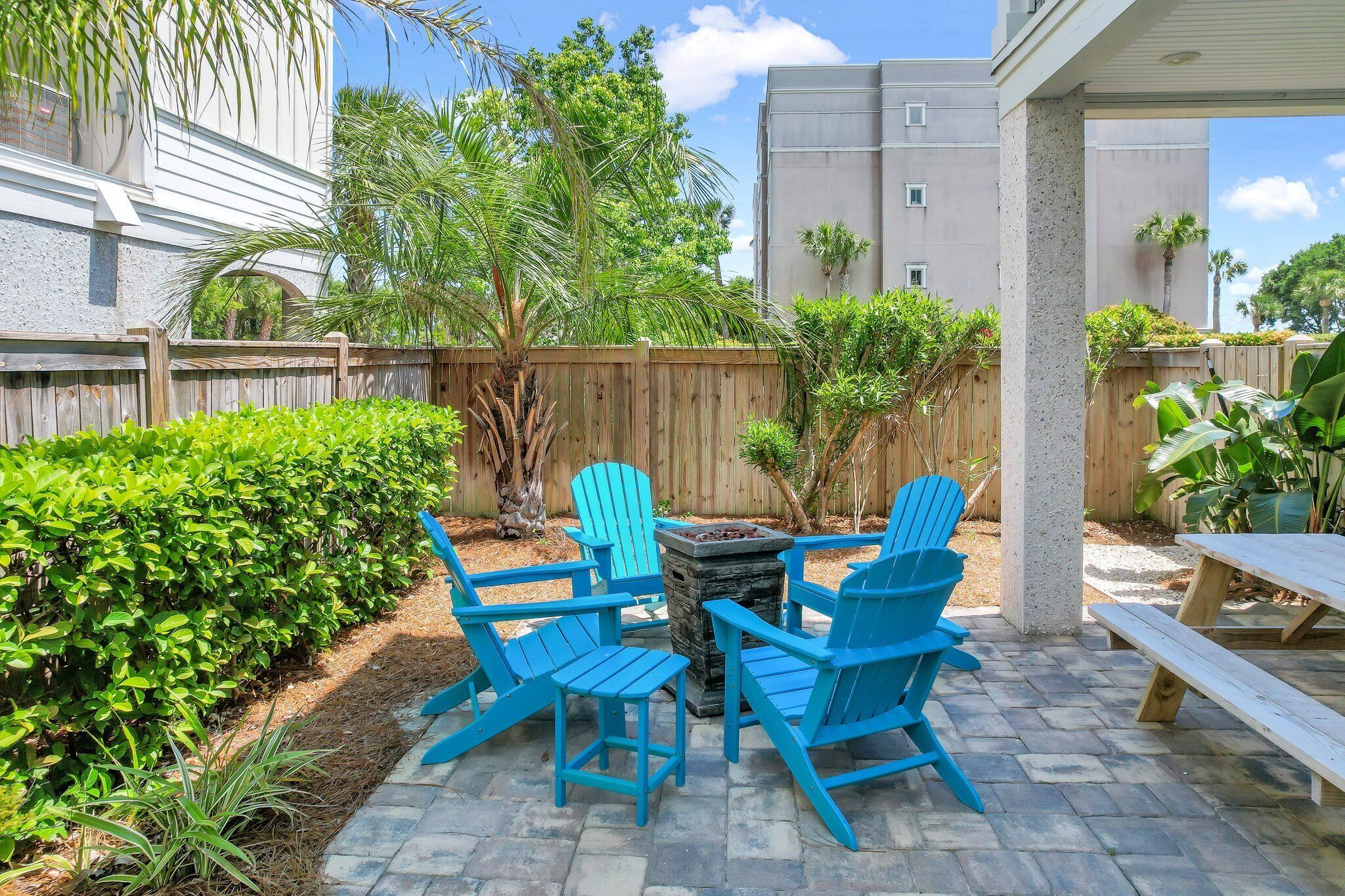 Un patio al aire libre con sillas Adirondack azules, un hogar de piedra y una mesa de madera.