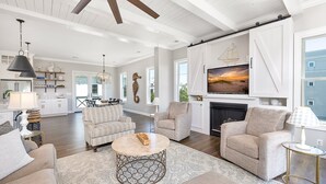 A spacious living room with a fireplace, a dining area, and a kitchen in the background. - Seahorse Villa! Amazing Ocean Views, Heated Pool, Private Elevator, Steps to Beach (Saint Simons Island)