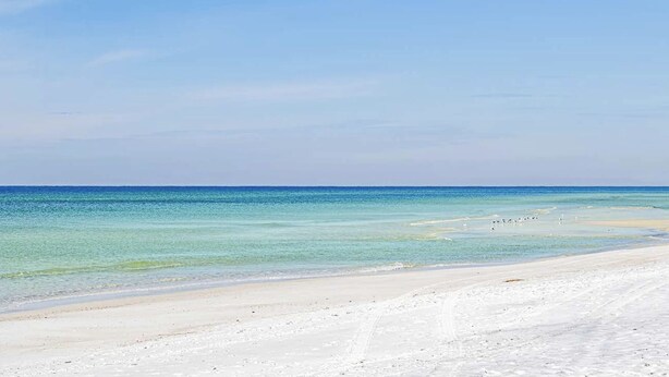 A beach with clear turquoise water and a sandy shore.
