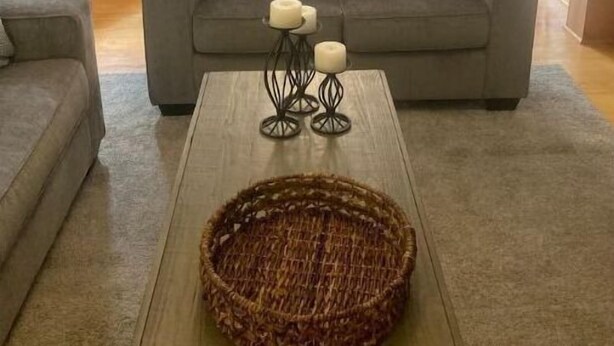 A living room with a grey sofa, a coffee table with candles, and a wicker basket. - Lakeview Cottage (Ballston Lake)