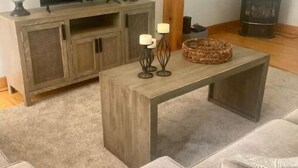 A living room with a wooden TV stand, a fireplace, and a sofa. - Lakeview Cottage (Ballston Lake)