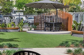 Relax in a serene outdoor seating area surrounded by lush greenery and a low wall.
