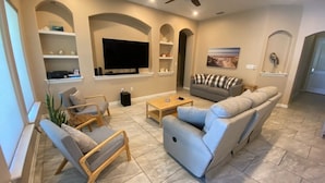 A modern living room with a flat-screen TV, a grey sofa, a wooden coffee table, and a grey armchair. - Single Family Home - 52 BP (Laguna Vista)