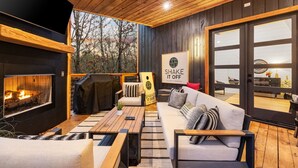 A cozy outdoor seating area with a fireplace, wooden furniture, and a sign that reads "SHAKE IT OFF."