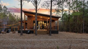 A rustic cabin with a porch, outdoor seating, and a fire pit.