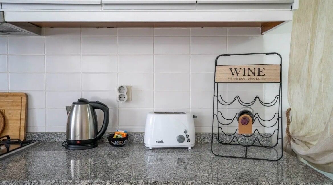 Una cucina con bollitore, tostapane e porta bottiglie.