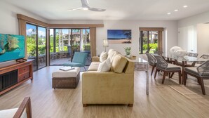 A spacious living room with a large sofa, a dining table with chairs, a television, and a ceiling fan. - Luxurious Oceanfront Condo at Wailea Elua Village - Unit 1201, Central AC, Wi-Fi (Kihei)