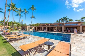 A pool area with lounge chairs and a building with large windows. - Luxurious Oceanfront Condo at Wailea Elua Village - Unit 1201, Central AC, Wi-Fi (Kihei)