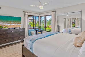 A bedroom with a large bed, a dresser, a ceiling fan, and a view of a garden through a sliding glass door. - Luxurious Oceanfront Condo at Wailea Elua Village - Unit 1201, Central AC, Wi-Fi (Kihei)