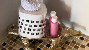A bathroom vanity with a white towel, a pink bottle, and a gold-colored tray.