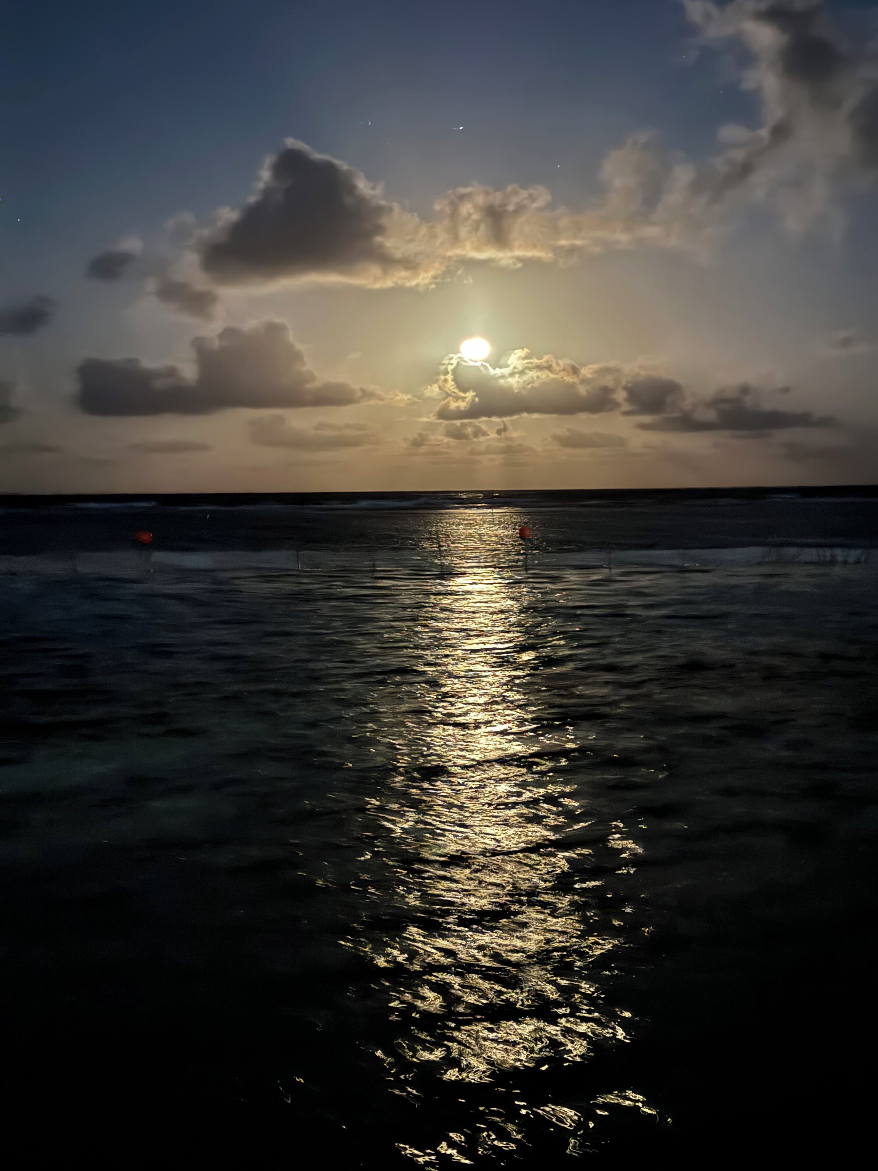 Un atardecer sobre el océano con un mar en calma que refleja el cielo.