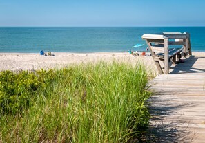 Ein hölzerner Steg führt zu einem Strand mit freiem Blick auf den Ozean.