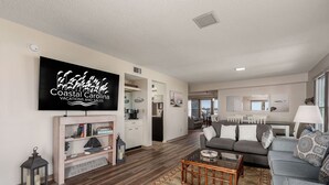 A spacious living room with a large flat-screen TV, a fireplace, and a cozy seating area. - Carolina Ocean Views: Dog Friendly, Ocean Views (Kill Devil Hills)
