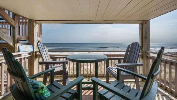 A wooden deck with Adirondack chairs and a table overlooking the ocean. - Carolina Ocean Views: Dog Friendly, Ocean Views (Kill Devil Hills)