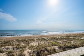 Une plage avec une promenade en bois qui mène au rivage, des dunes de sable et l’océan.